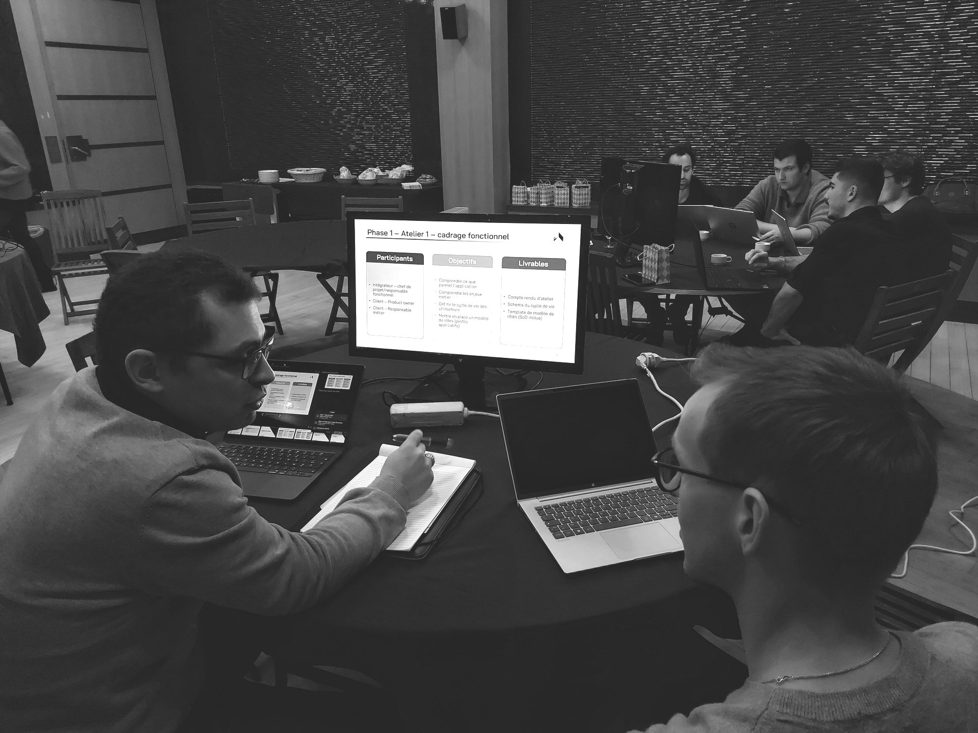 Deux consultants Ariovis en atelier de cadrage fonctionnel, devant une présentation détaillant participants, objectifs et livrables.